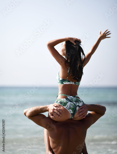Happy cheerful couple have fun girl sitting  on boyfriend shoulders. Romantic vacation, honeymoon love photo