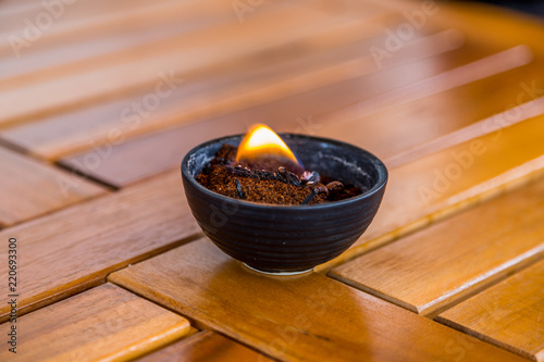 Brennendes Kaffeepulver in einer Schale auf einer Holzplatte