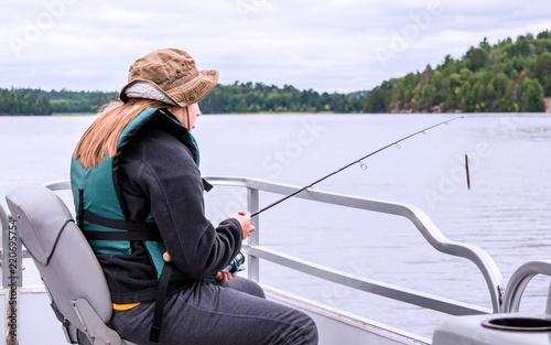 A young girl with brunette hair is fishing in a lake © Yan