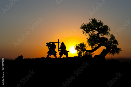 Silhouette of two samurais in duel. Picture with two samurais and sunset sky. Selective focus