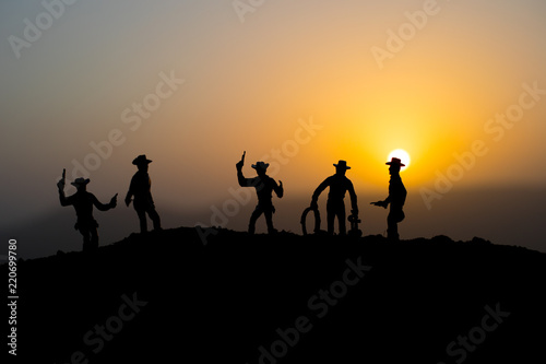 Cowboy concept. Silhouette of Cowboys at sunset time. A cowboy silhouette on a mountain with an yellow sky. © zef art