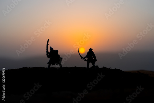 Medieval battle scene on sunset. Silhouettes of fighting warriors on sunset background. © zef art