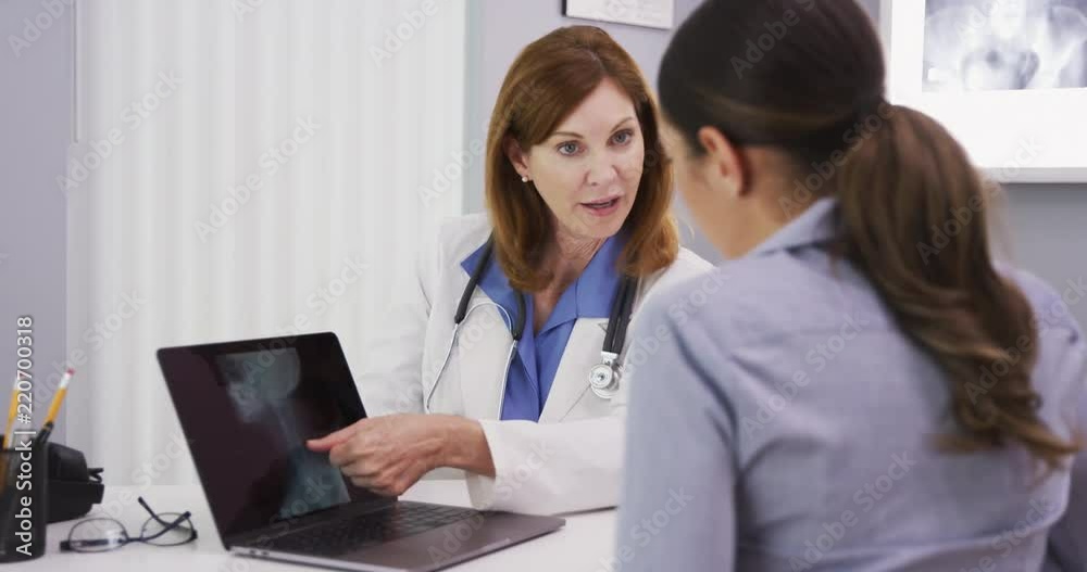 Senior doctor showing xray of spine neck and cranium to young female patient Senior doctor showing xray of spine neck and cranium to young female patient