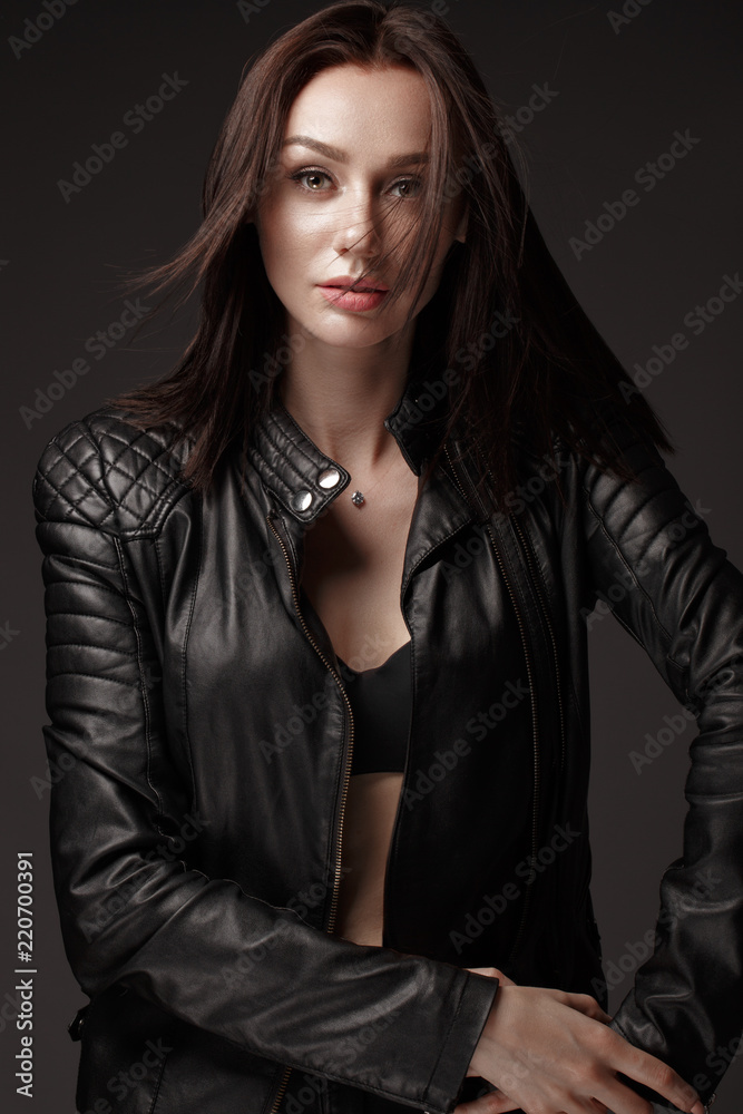 Daring girl model in black leather dress, style of rock, dark make up and beauty hair. Picture taken in the studio.
