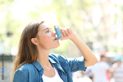 Canvas Print Asthmatic woman using a inhaler outdoors