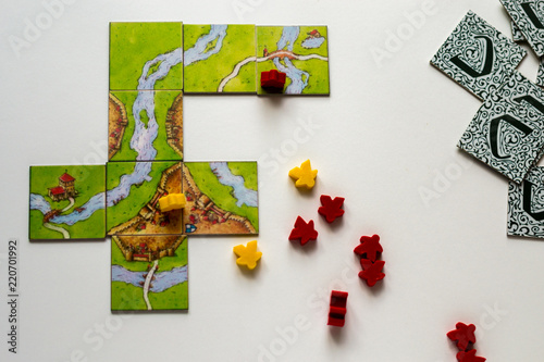 Close up red and yellow meeples in hand isolated on white background. Components of board games. Small figures of people's body in hand. Vacation time. Gameplay.
