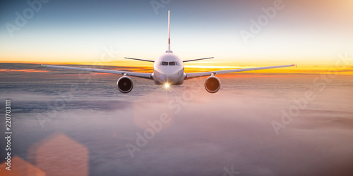 Commercial airplane flying above dramatic clouds.
