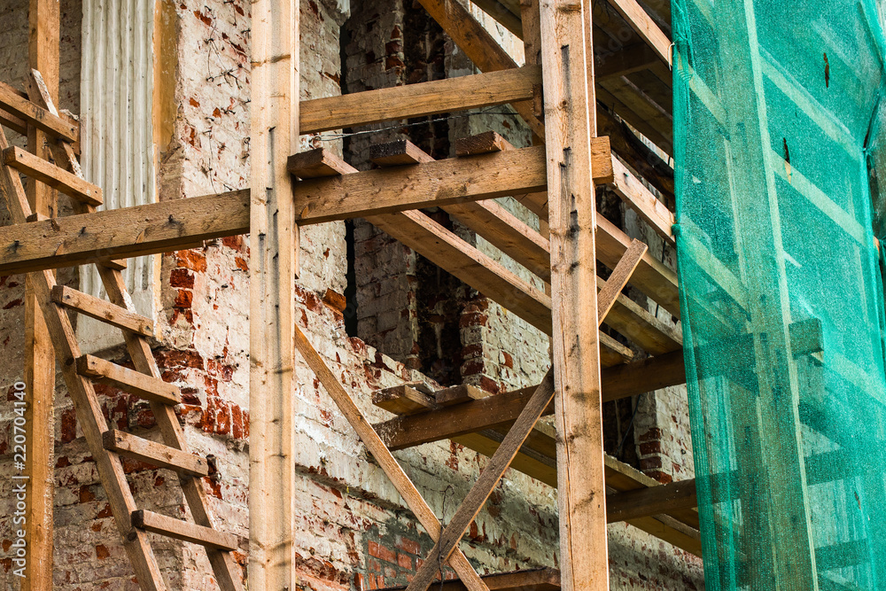 Wooden scaffolding near the old building and a protective mesh Wooden scaffolding near the old building and a protective mesh