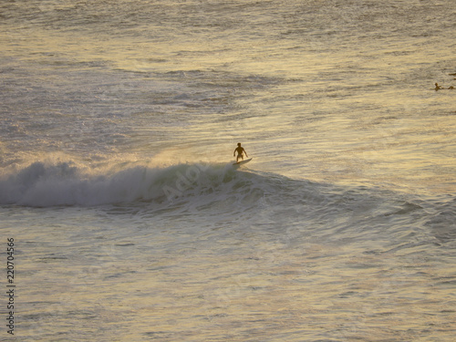 Surfers riding waves during sunset session at a surfer spot in Bali, Indonesia Uluwato, Bingin photo