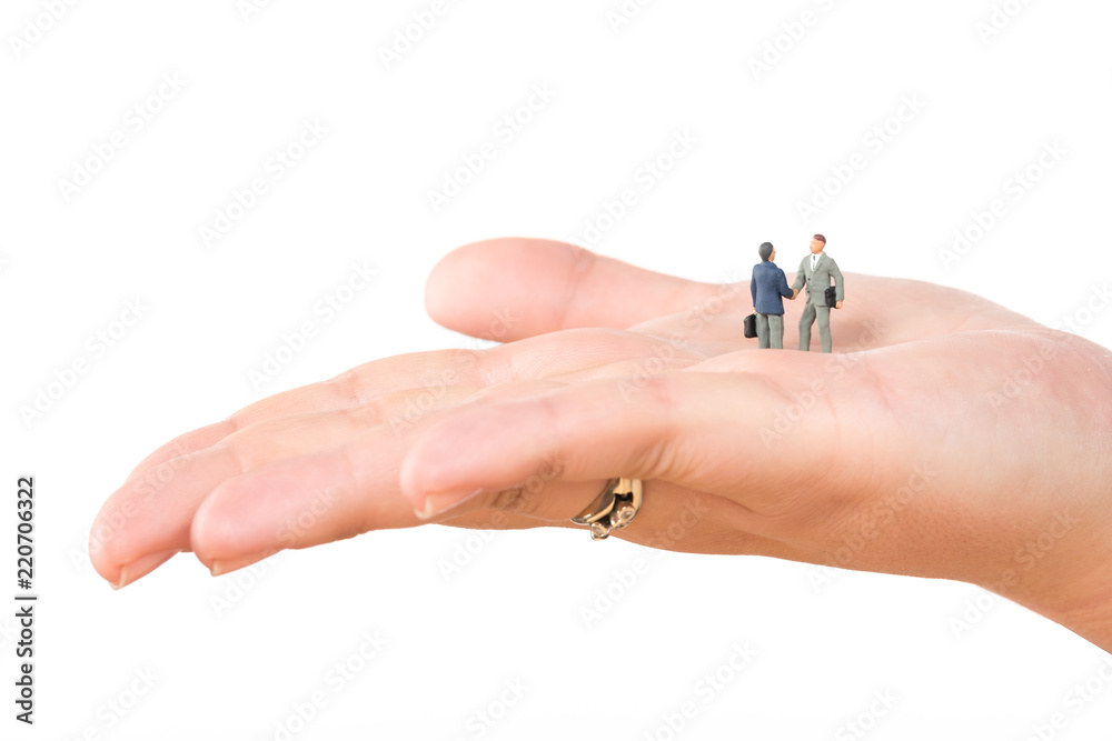 Two miniature businessmen shaking hands on female hand isolated on white background. Business deal or agreement and success concept. Two miniature businessmen shaking hands on female hand isolated on white background. Business deal or agreement and success concept.