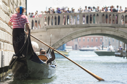 Venice, Italy - May 21, 2017: The gondola floats along the old narrow street in Venice. Gondola is the most attractive tourist transport in Venice. photo