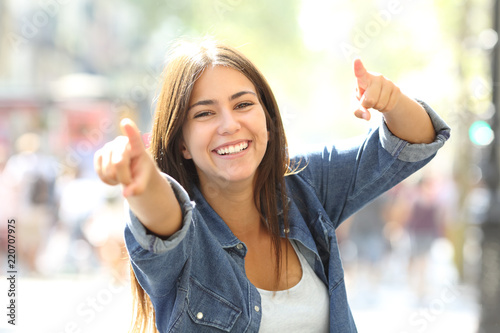 Joyful girl pointing at camera in the street