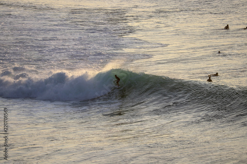 Surfers riding waves during sunset session at a surfer spot in Bali, Indonesia Uluwato, Bingin