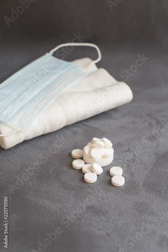 medical gauze, pills and medical mask are on grey background (vertically)