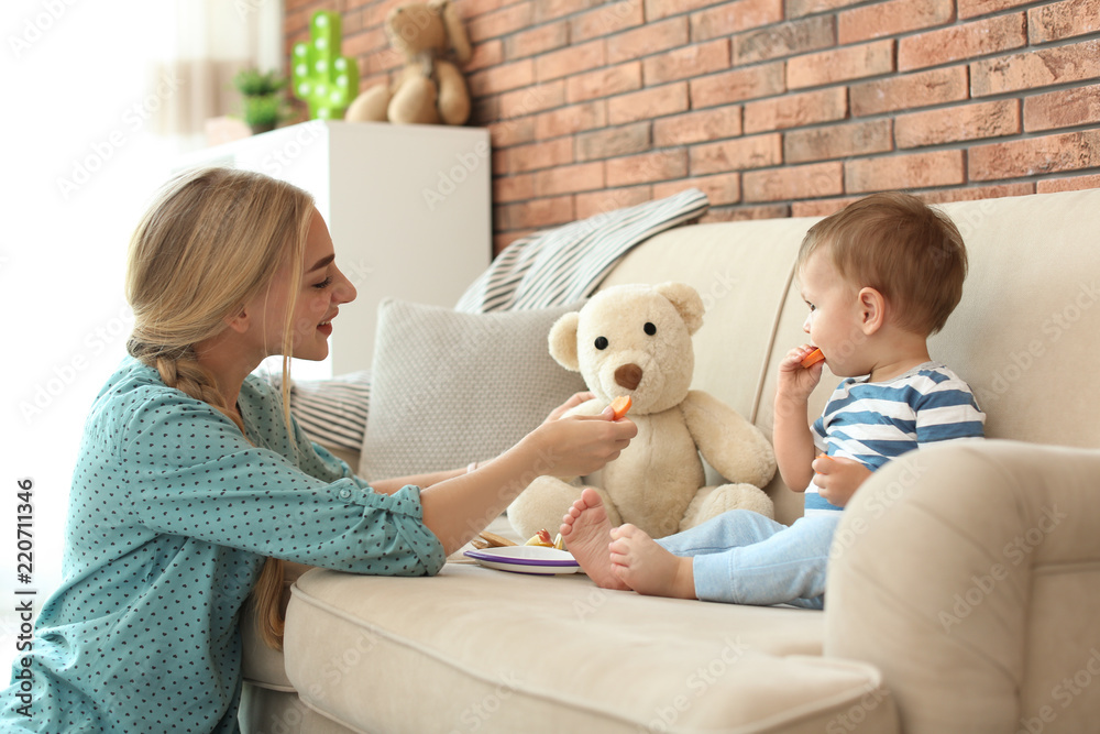 Woman playing with child while feeding him at home. Healthy baby food Woman playing with child while feeding him at home. Healthy baby food