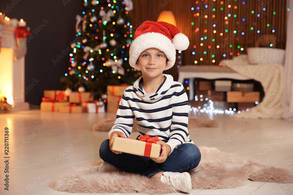 Cute little child in Santa hat with Christmas gift box at home Cute little child in Santa hat with Christmas gift box at home