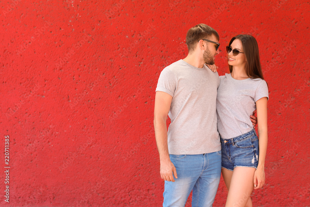 Young couple wearing gray t-shirts near color wall on street