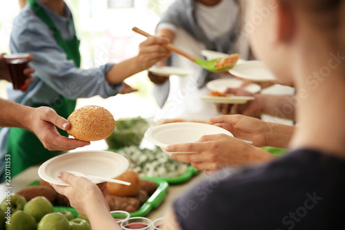 Volunteers serving food for poor people indoors