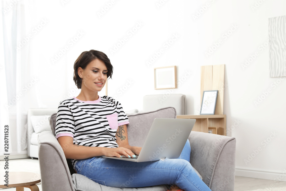 Young woman with modern laptop sitting in armchair at home Young woman with modern laptop sitting in armchair at home