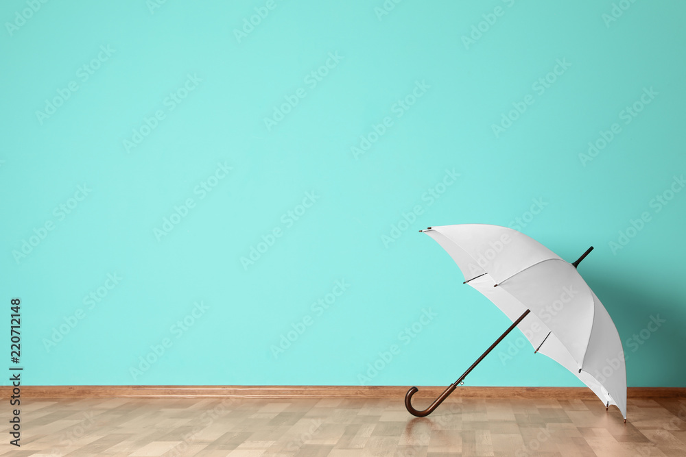 Beautiful open umbrella on floor near color wall with space for design - obrazy, fototapety, plakaty 