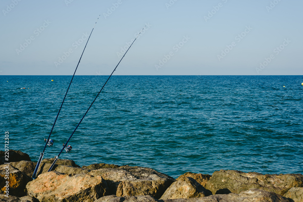 Fishing rods fixed to the rocks near the sea coast without fishermen