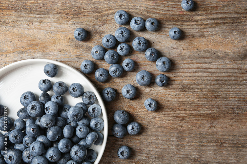 Flat lay composition with juicy and fresh blueberries on wooden table Flat lay composition with juicy and fresh blueberries on wooden table