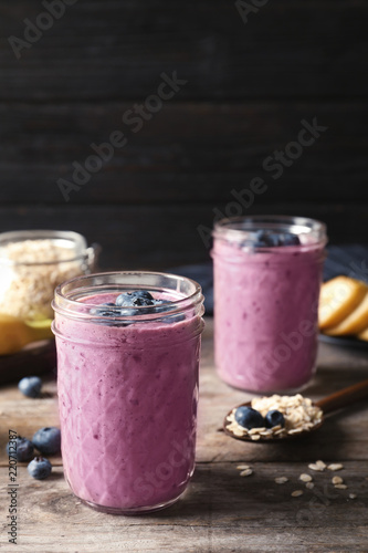 Jars with blueberry smoothies on wooden table