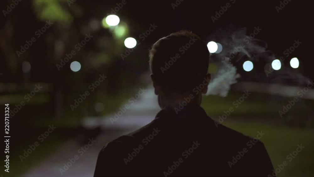 The man walking on the night street and smoking. slow motion