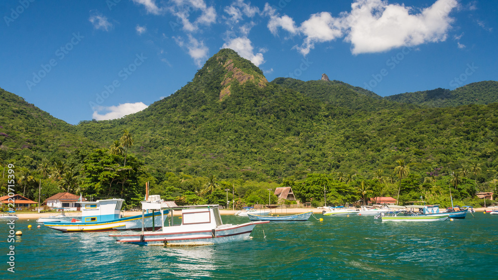 Big Island seen from the sea with fisher boats on the clear warm water and a mountain in the background on a summer sunny day