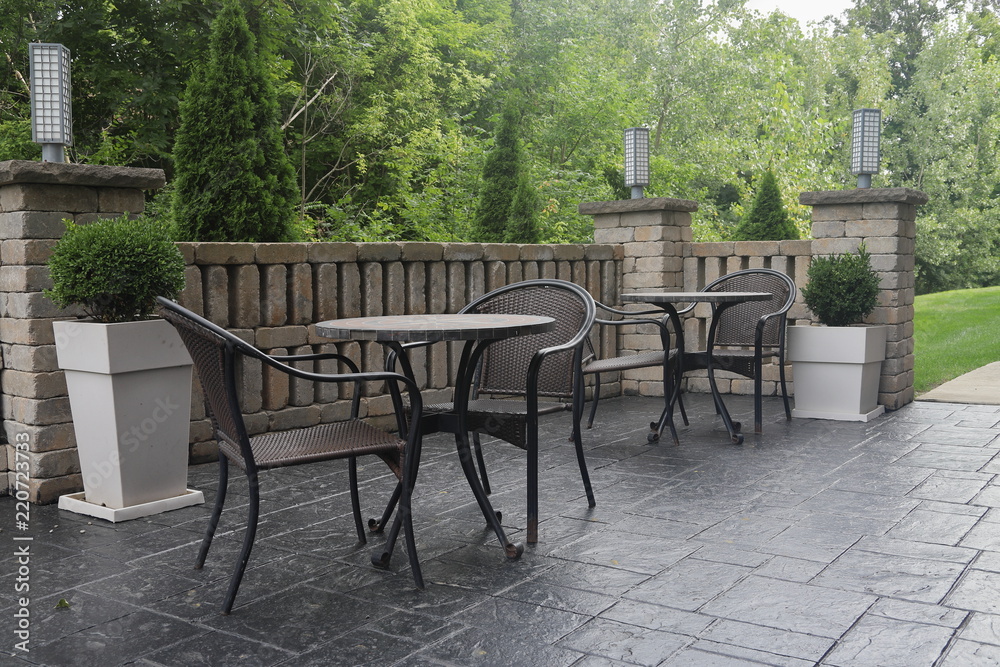 Two Tables and Chairs on hotel patio in the morning sunlight with greenery in the background