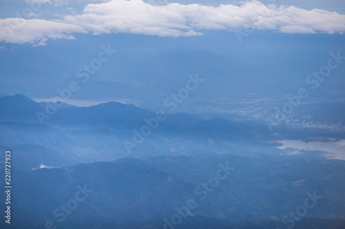 Background, high angle from the passenger plane. You can see the scenery by the distance (mountains, rivers, sky, fog, houses), the photos may be blurred during the flight.