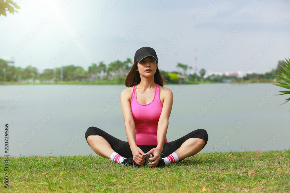 Young fitness woman runner sitting stretching legs before run on park. Young fitness woman runner sitting stretching legs before run on park.