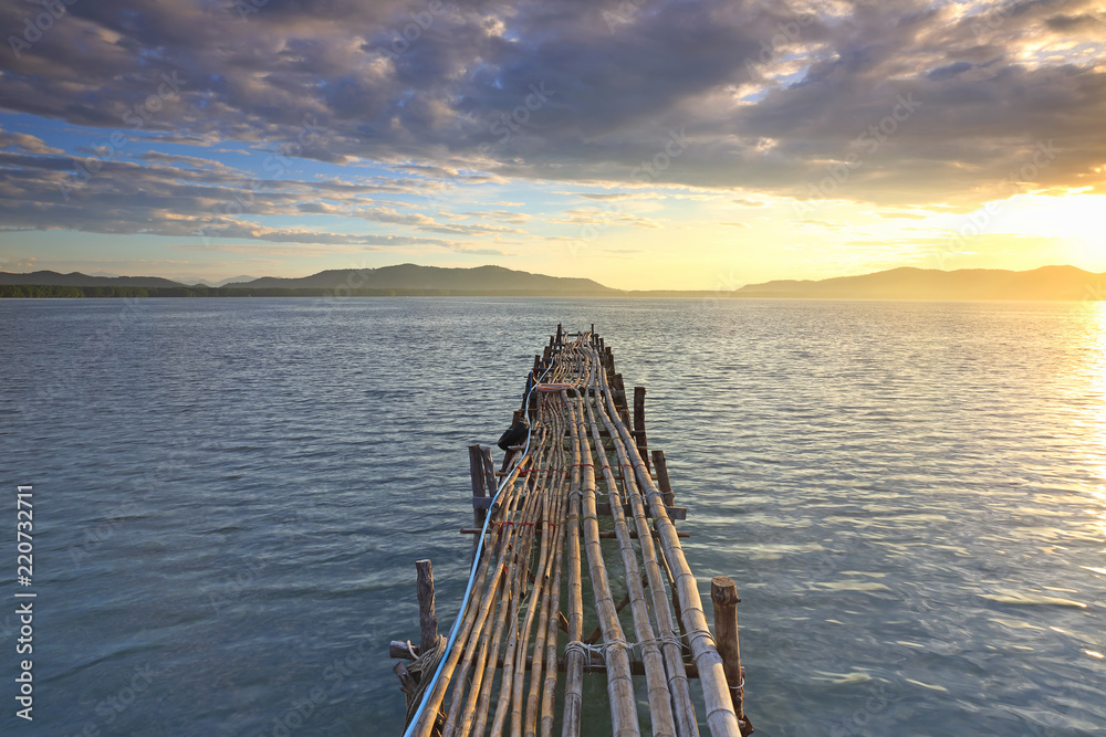 View of  wooden pier on the amazing idyllic of the fishing village and tropical ocean in the sunrise, Gulf of Thailand