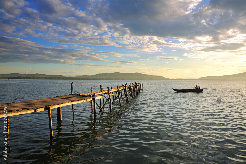 Obraz premium View of wooden pier on the amazing idyllic of the fishing village and tropical ocean in the sunrise, Gulf of Thailand
