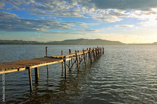 View of  wooden pier on the amazing idyllic of the fishing village and tropical ocean in the sunrise  Gulf of Thailand