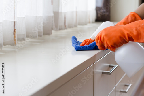 Obraz na płótnie Hand in gloves spraying a cleanser to a wooden furniture for cleaning a dust in bedroom