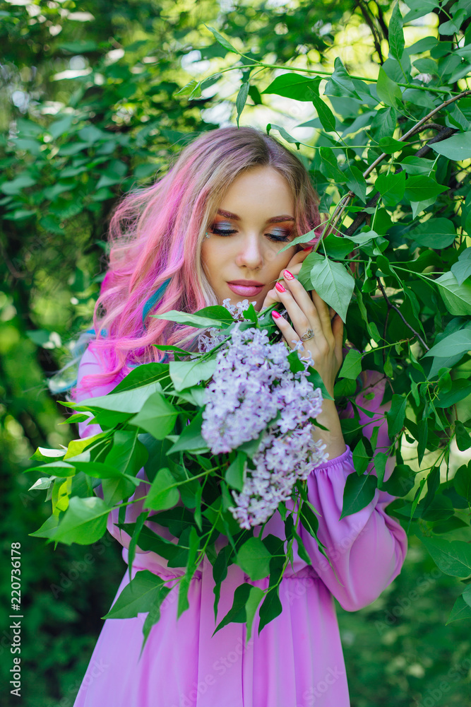 Beautiful girl with colorful dyed hair and perfect makeup standig next to lilac bush Beautiful girl with colorful dyed hair and perfect makeup standig next to lilac bush