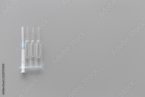 Flu vaccination concept. Syringe and ampoulie on grey background top view space for text