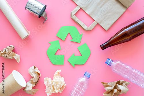 Recycling. Green recycle eco symbol. Recycled arrows sign near matherials for recycle and reuse on pink background top view photo