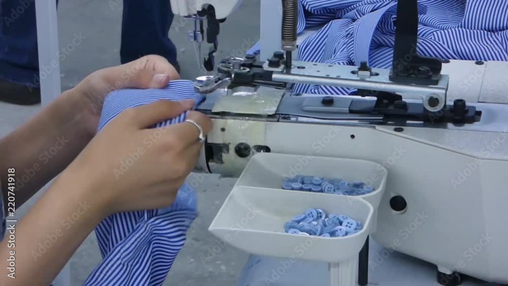 the woman in the workshop sews buttons to the shirt