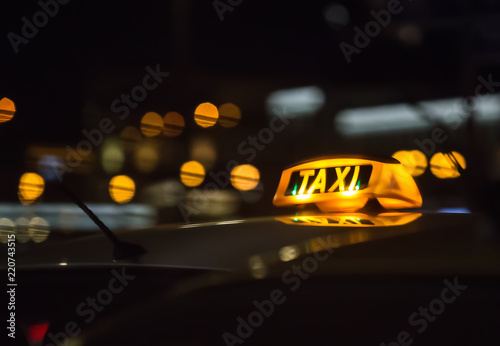 illuminated sign taxi on the roof of the car at night