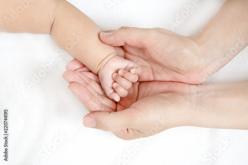 赤ちゃんの小さな手を包むお母さんの大きな両手のアップ。成長と健康を喜ぶ母。母性、愛情、幸せ、育児、健康のイメージ
