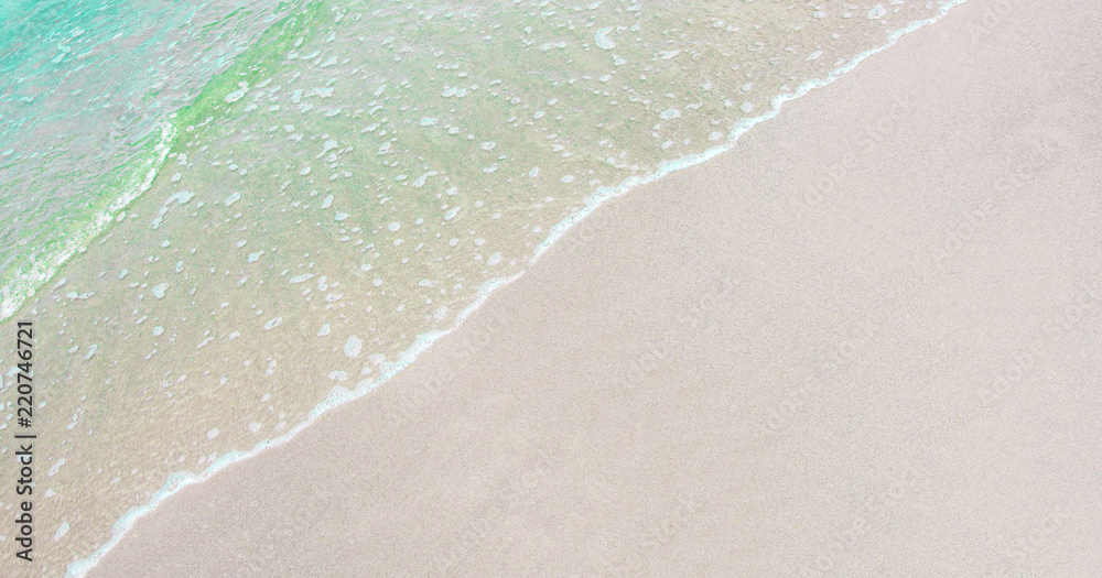 Soft wave of Emerald green ocean on sandy beach with copy space on background.