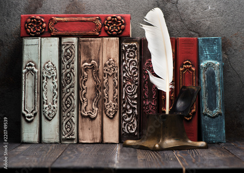 Ancient books on shelf and antique inkwell with feather
