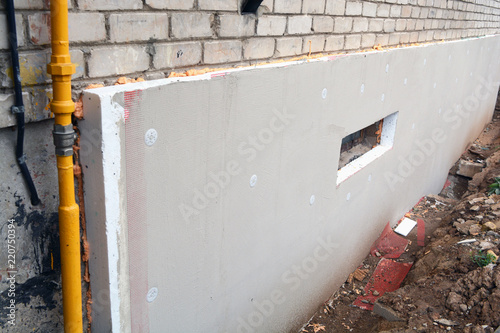 Insulating old  flat house foundation with white polystyrene