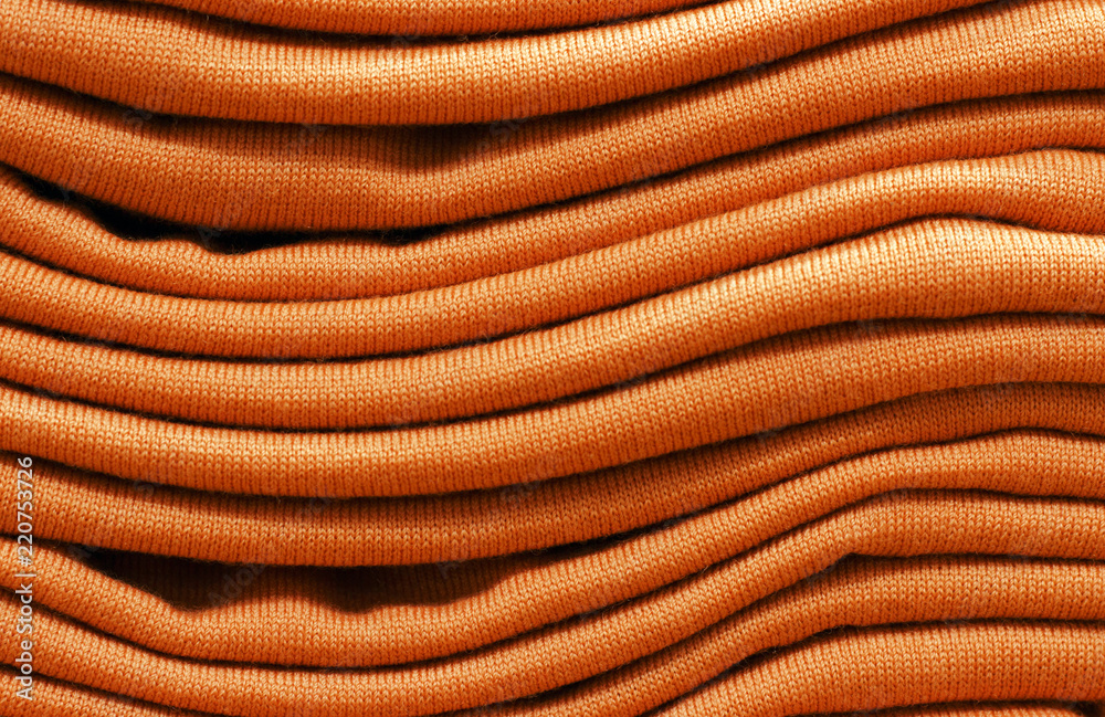 Stack of russet orange woolen knitted sweaters close-up, texture, background