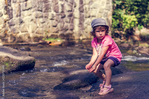 Fototapeta Naklejka Na Ścianę i Meble -  The little girl is playing in a mountain stream
