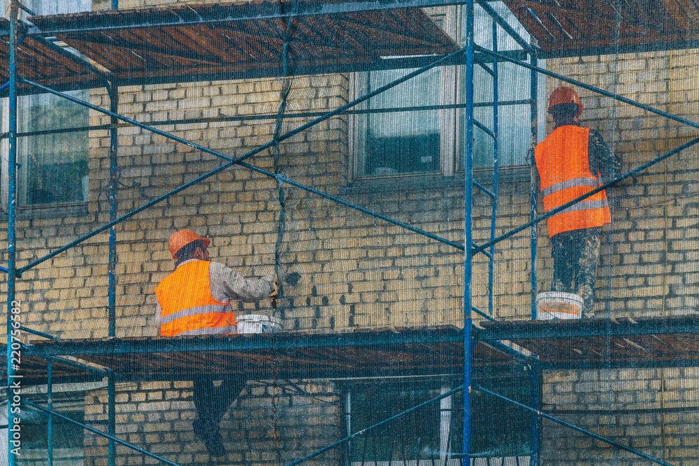 Naklejka premium workers repair the facade of the building