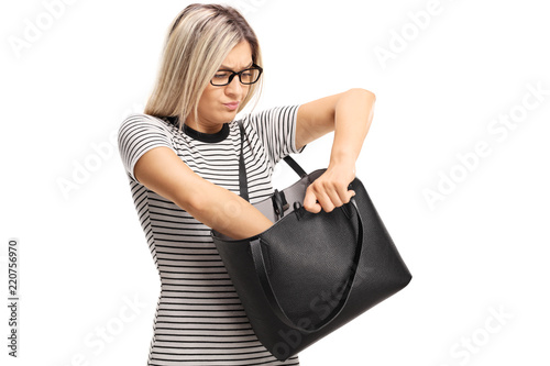 Angry young woman searching in her handbag photo