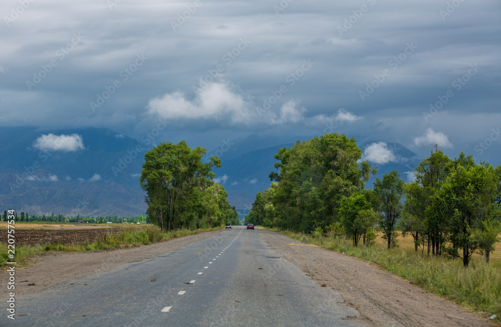 Mountain road. Landscape with rocks, sunny sky with clouds and beautiful asphalt road in the evening in summer. Vintage toning. Travel background. Highway in mountains. Transportation